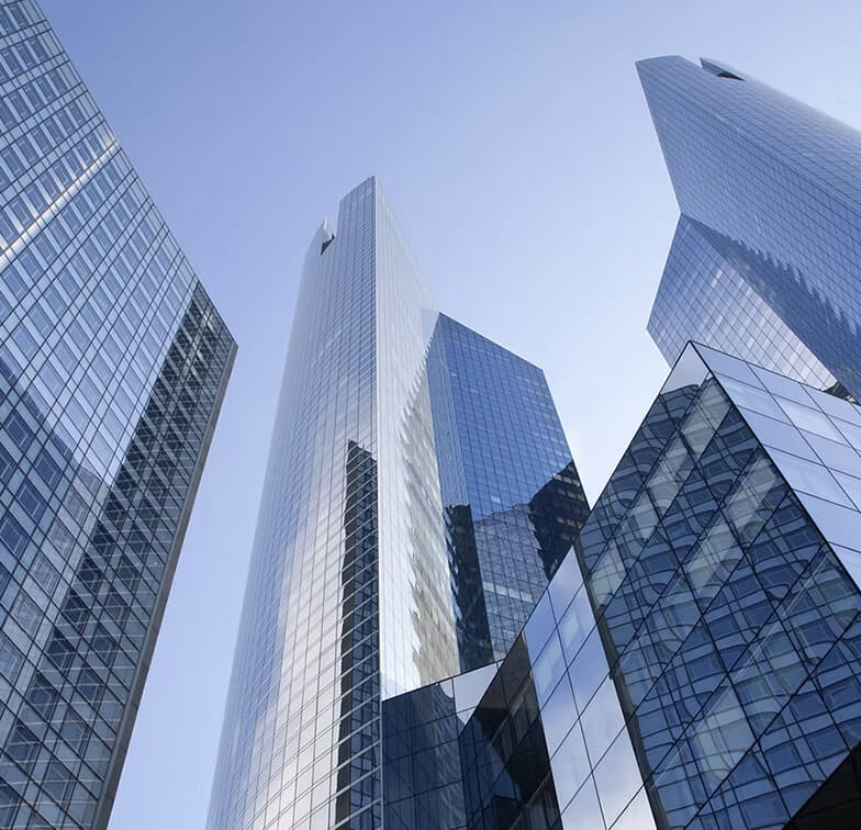 A view of modern skyscrapers with reflective glass surfaces against a clear blue sky, showcasing contemporary architectural design.