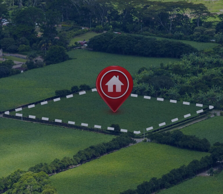 Aerial view of a green field with a house icon marking a property boundary and surrounded by lush vegetation.