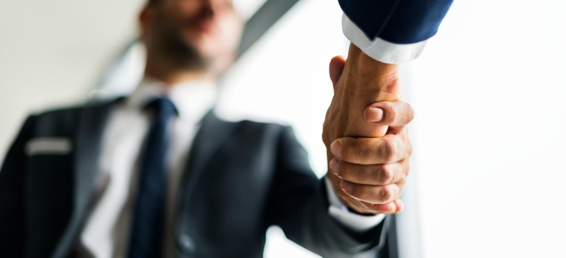 Two business professionals shaking hands in a bright office setting, signifying a successful agreement or partnership.