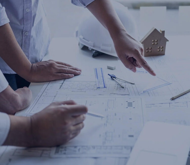 Two individuals collaborate on a blueprint featuring a house design on top, discussing plans and ideas.