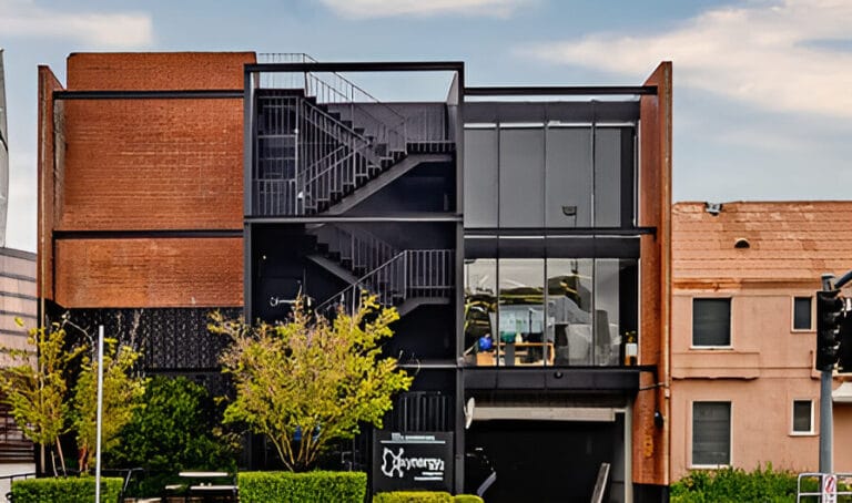 A building featuring a staircase leading up to a prominent black door.