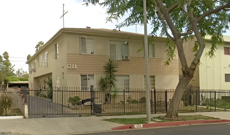 A house with a fence and a parked car in front, showcasing a suburban residential setting.