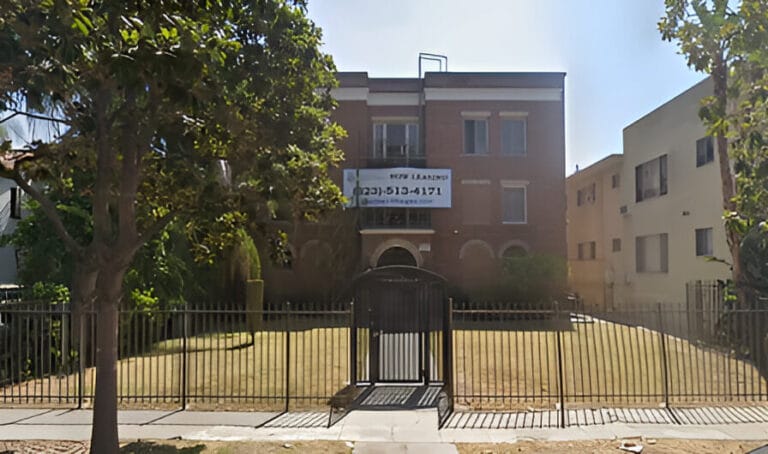 A large building with a fence and gate in front, showcasing its entrance and surrounding area.