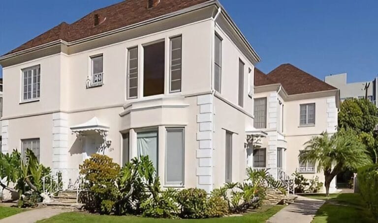 A large white house surrounded by a spacious green lawn.
