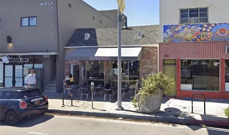 A street view of a restaurant with a car parked in front, showcasing the entrance and surrounding area.