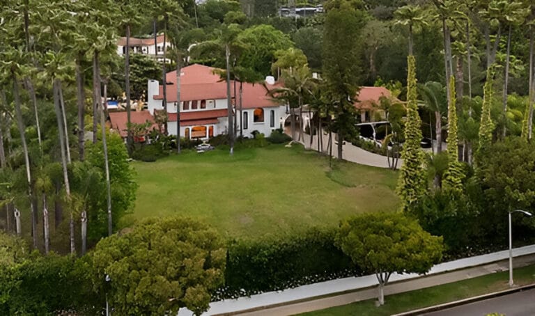 Aerial view of a large house nestled among lush green trees, showcasing its expansive surroundings.
