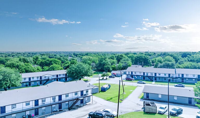 Aerial view of a residential apartment complex featuring multiple buildings and adjacent parking lots.