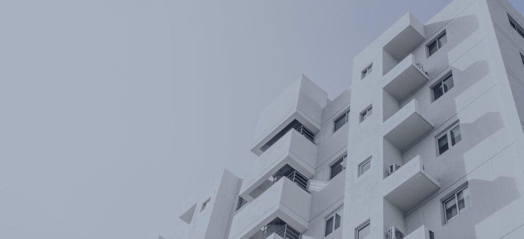 Modern apartment building with geometric white balconies against a light gray sky, showcasing contemporary architectural design.