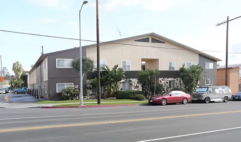 View of an apartment complex situated on the corner of a street, showcasing its contemporary design and entrance.